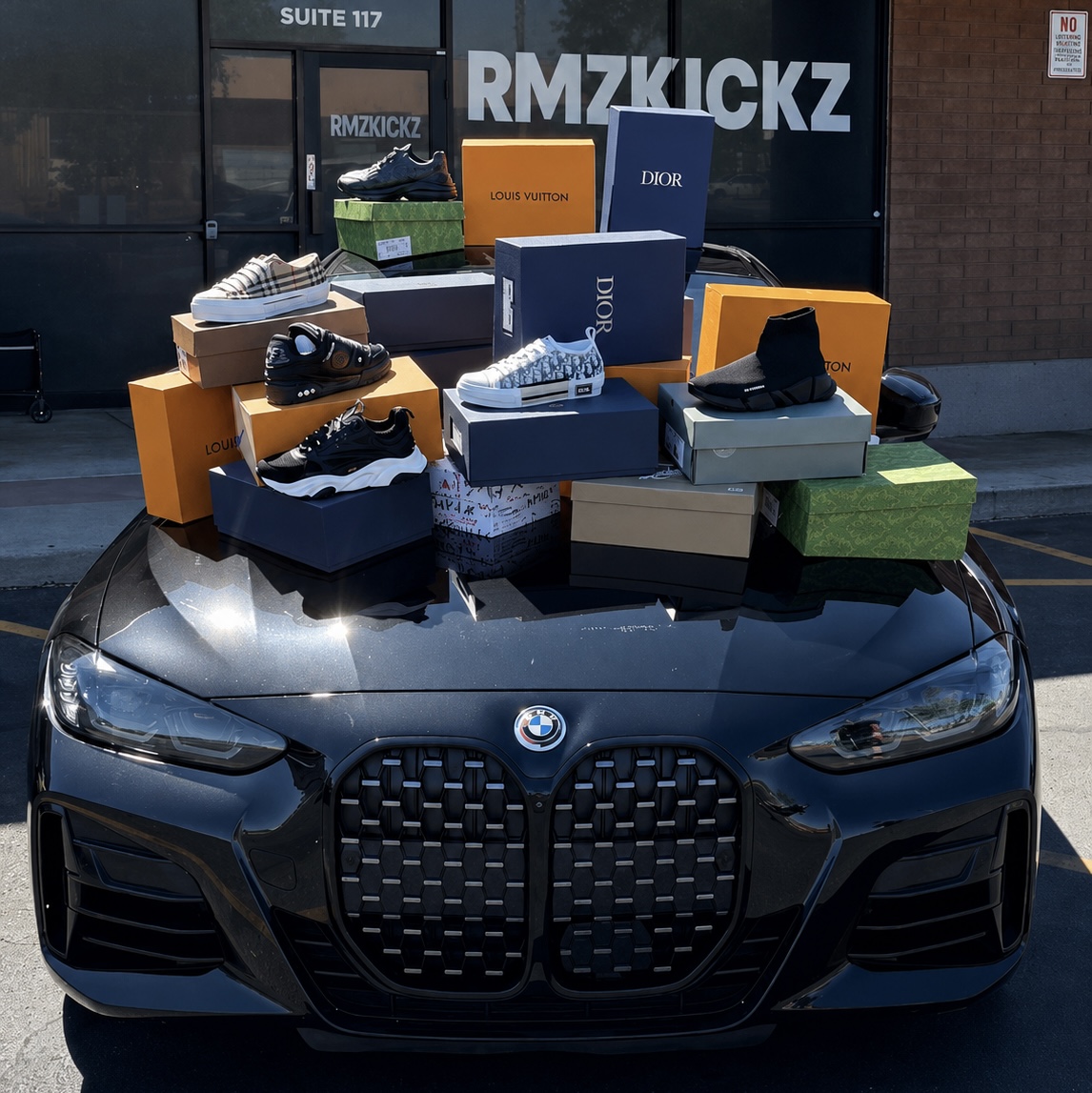 RMZKICKZ storefront with luxury sneaker boxes stacked on BMW